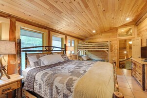 Un dormitorio de cabaña de madera con una cama, un aparador y un televisor.