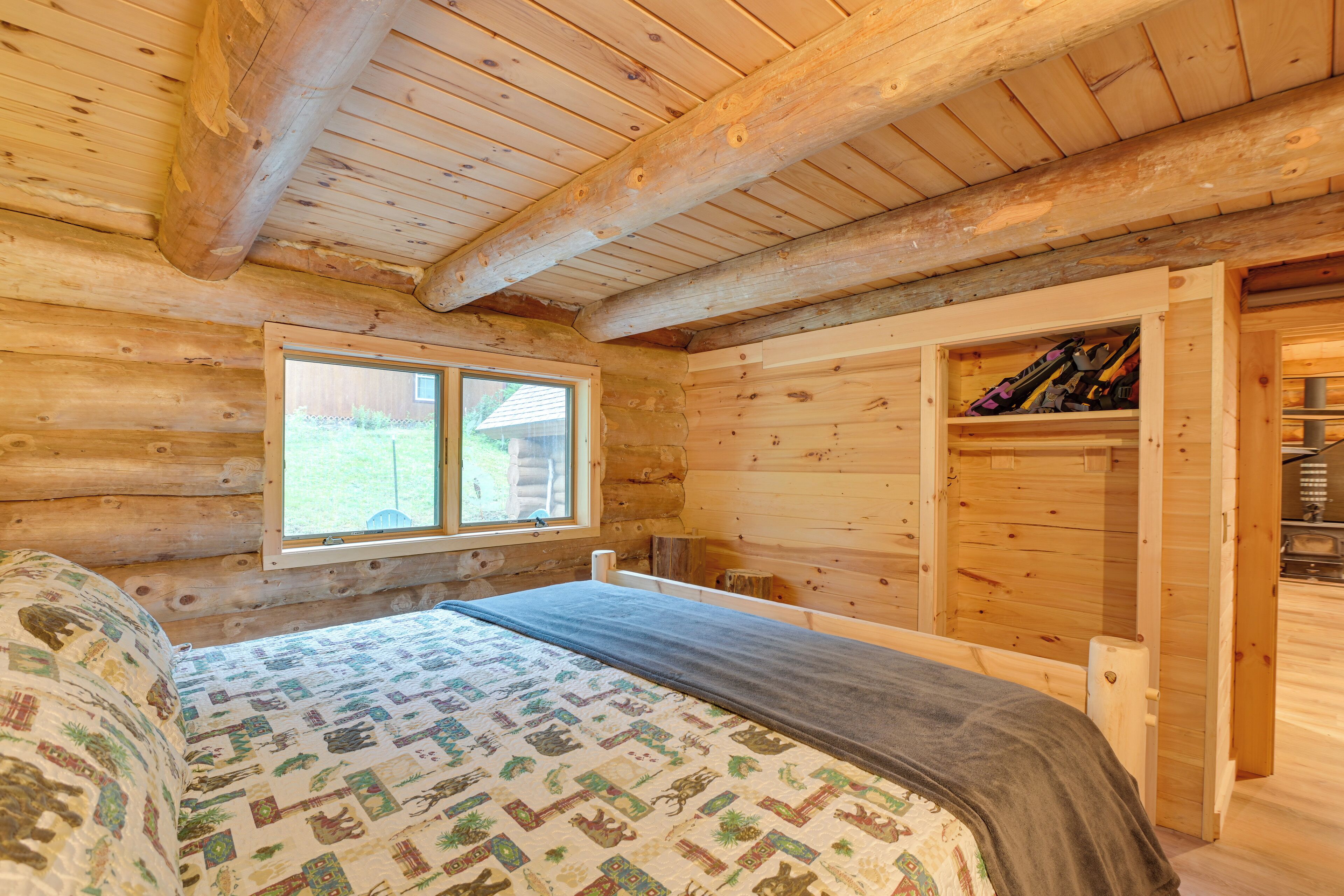 Een slaapkamer in een blokhut met een bed, een raam en een inbouwkast.