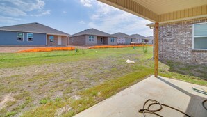 A residential area with houses under construction, a covered porch, and a grassy yard. - Charming Arkansas Getaway - Walk to Downtown! (Fort Smith)