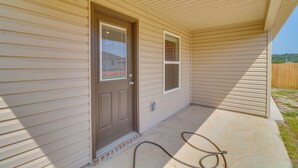 A house with a beige exterior, a brown front door, and a small window. - Charming Arkansas Getaway - Walk to Downtown! (Fort Smith)
