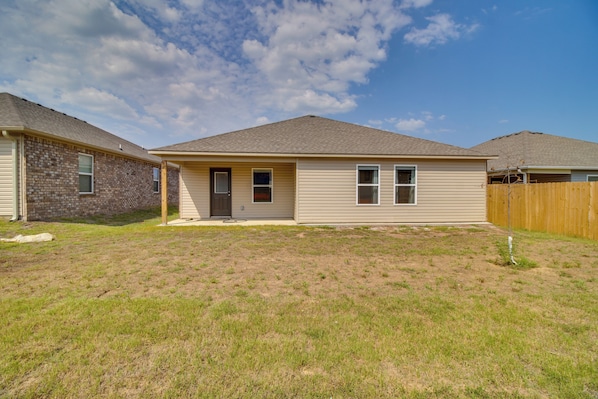 A two-story house with a front yard, a wooden fence, and a clear sky. - Charming Arkansas Getaway - Walk to Downtown! (Fort Smith)