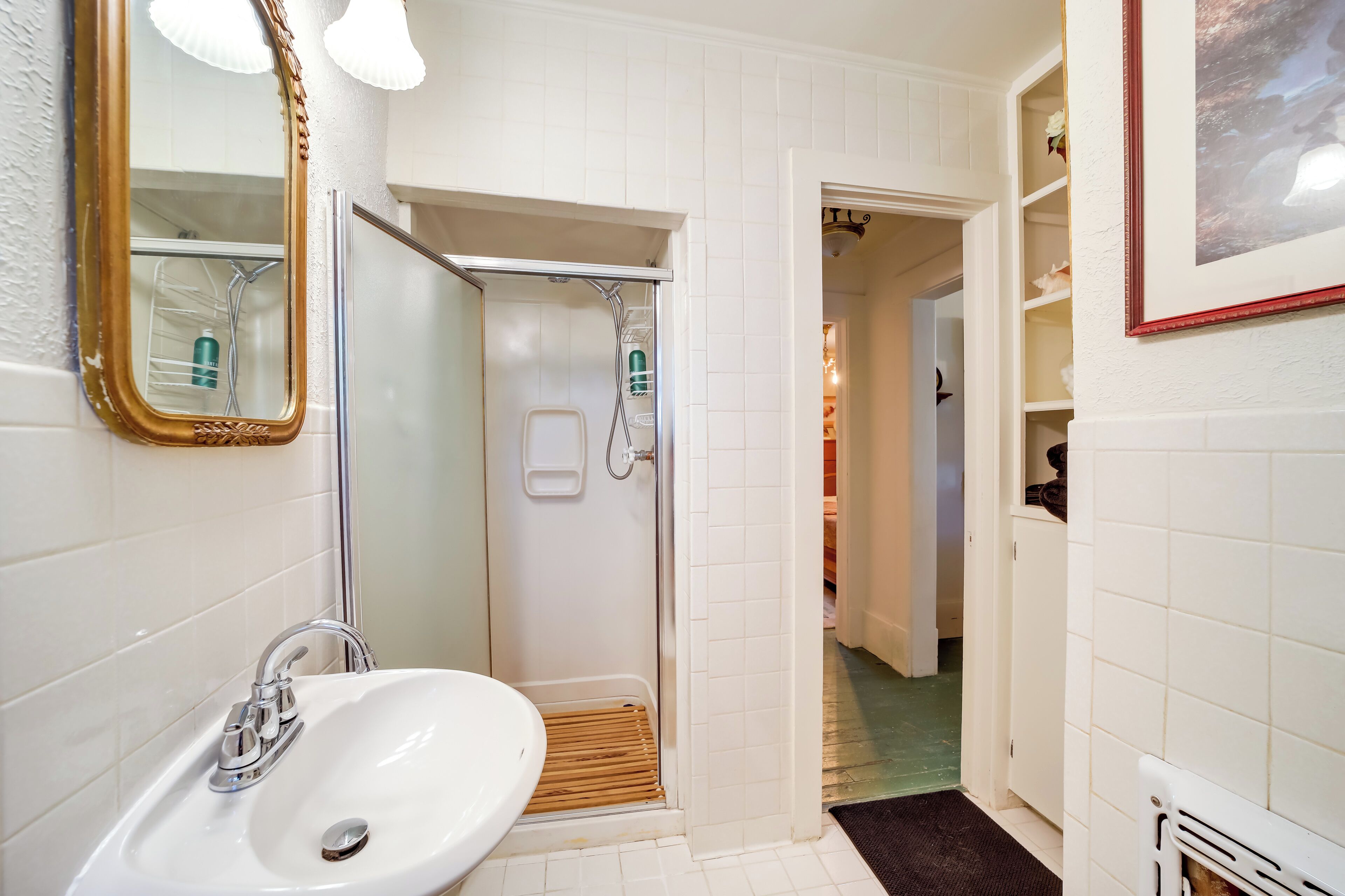 A bathroom with a white sink, a mirror, and a shower.