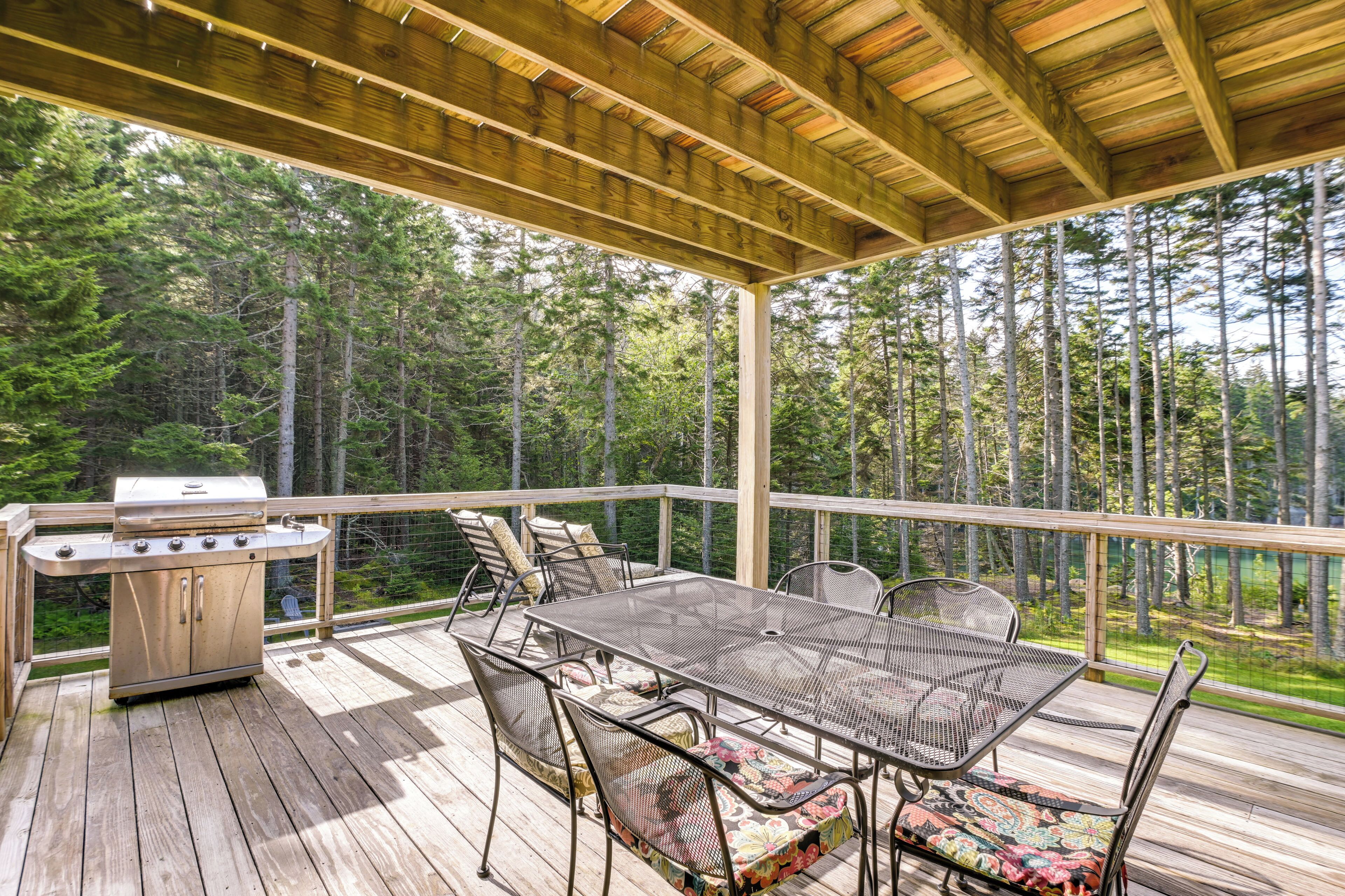 A covered outdoor deck with a grill, dining table, and chairs.