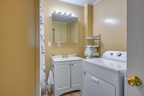 Un baño con lavamanos, espejo y lavadora.