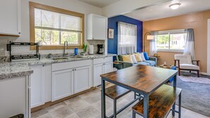 Una cocina moderna con armarios blancos, encimera de granito y mesa de comedor de madera.