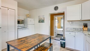 Una cocina con armarios blancos, una mesa de madera y un reloj en la pared.