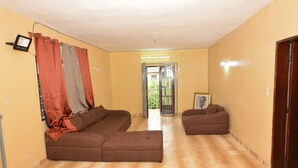 Una sala de estar con un sofá seccional marrón, un sofá más pequeño y un cuadro en la pared.