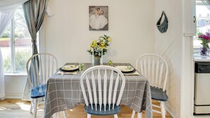 A dining area with a table set for four, white chairs, a gray checkered tablecloth, a vase with flowers, and a painting on the wall. - Gillette Adventure Base 1 Mi to Historic Downtown! (Gillette)