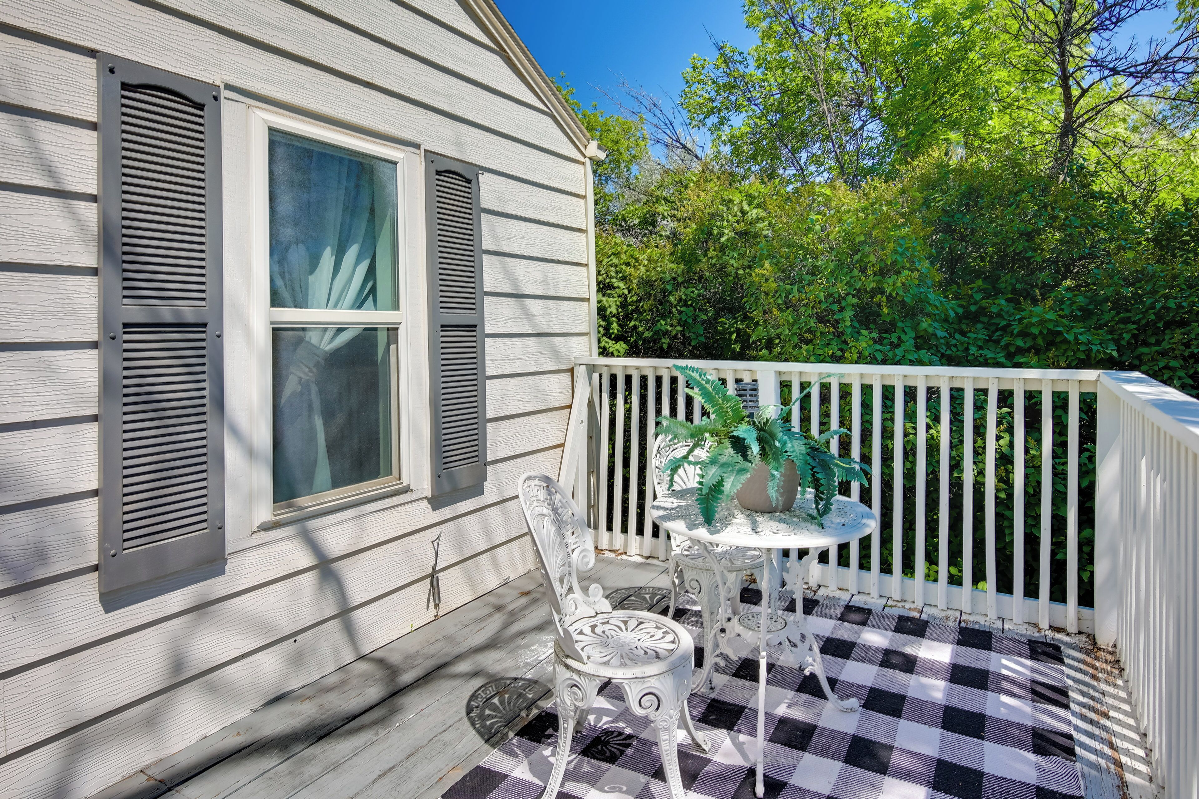 A porch with a checkered floor, a white railing, and a table with chairs.