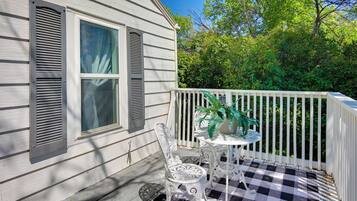 A porch with a checkered floor, a white railing, and a table with chairs.