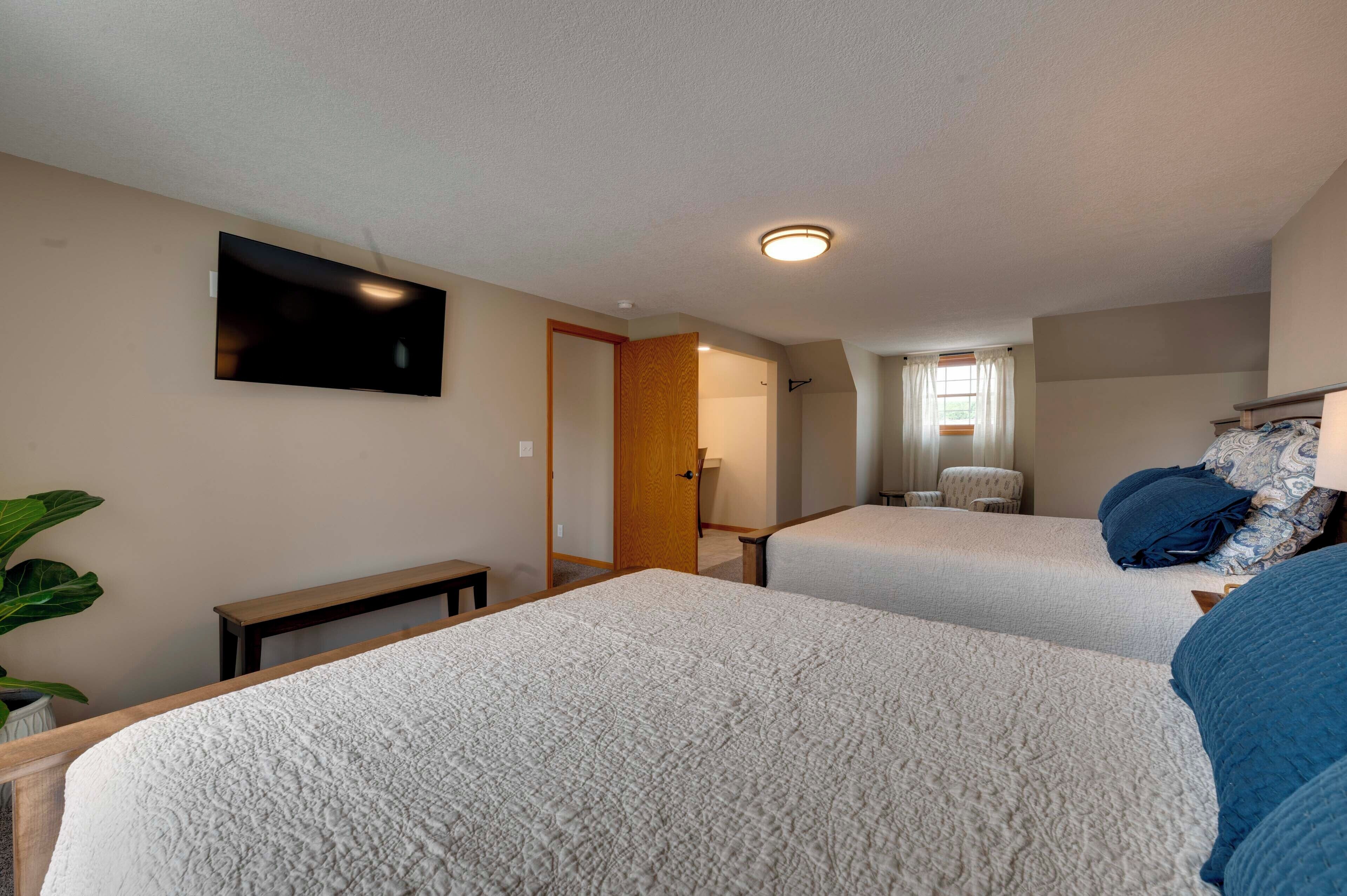 Een hotelkamer met twee bedden, een flatscreen televisie, een klein bureau en een kamerplant.