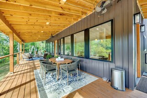 Una terraza techada al aire libre con techo de madera, ventanas amplias y un comedor con sillas y mesa.