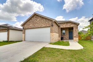 A two-story house with a brick facade, a white garage door, and a front door. - Jarrell Home w/ Playground + Pool Access! (Jarrell)