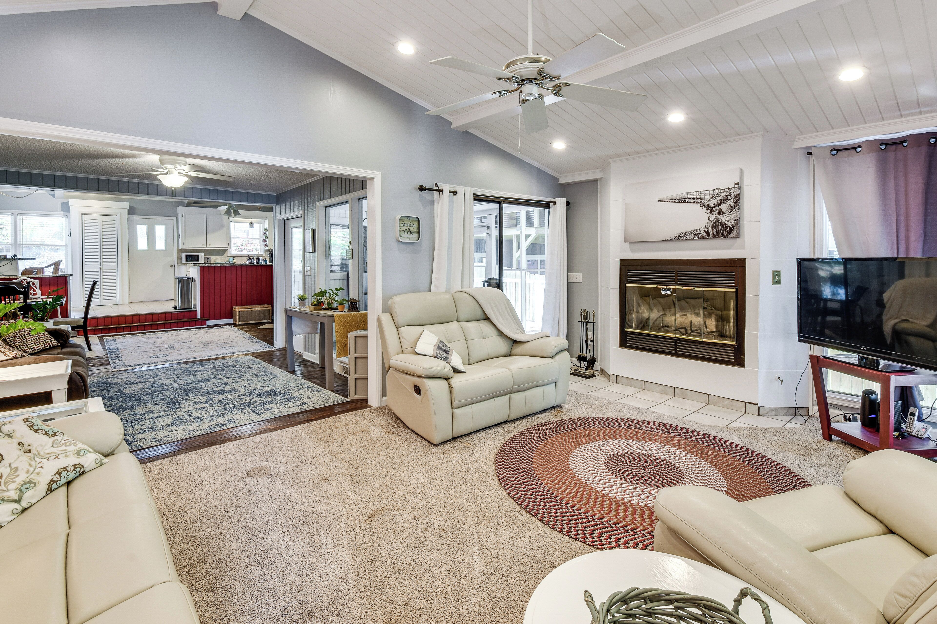 A living room with a sofa, a television, a fireplace, and a ceiling fan.