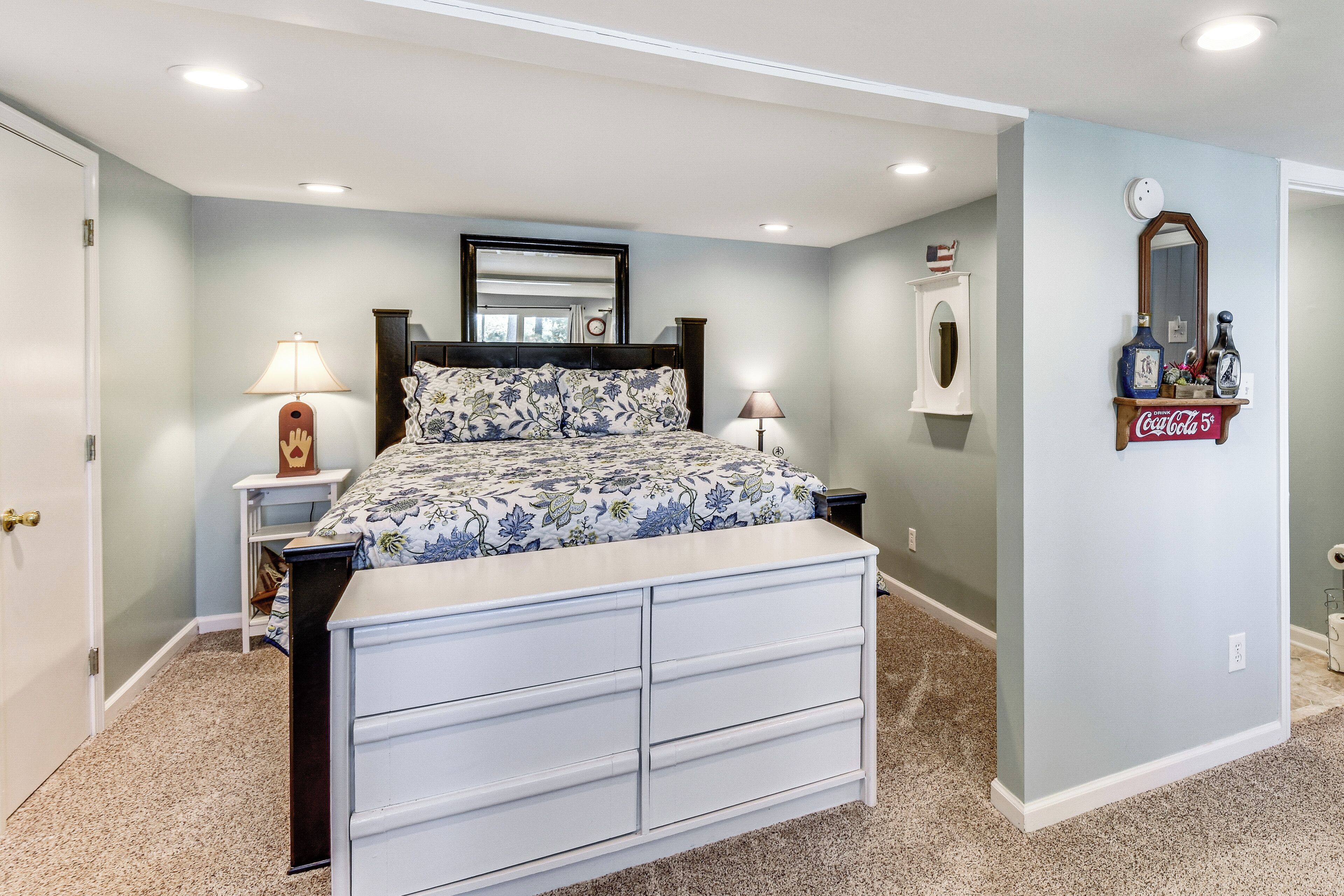 Une chambre à coucher comprenant un lit, des tables de chevet, une commode, un miroir et une étagère murale sur laquelle sont posés divers objets.