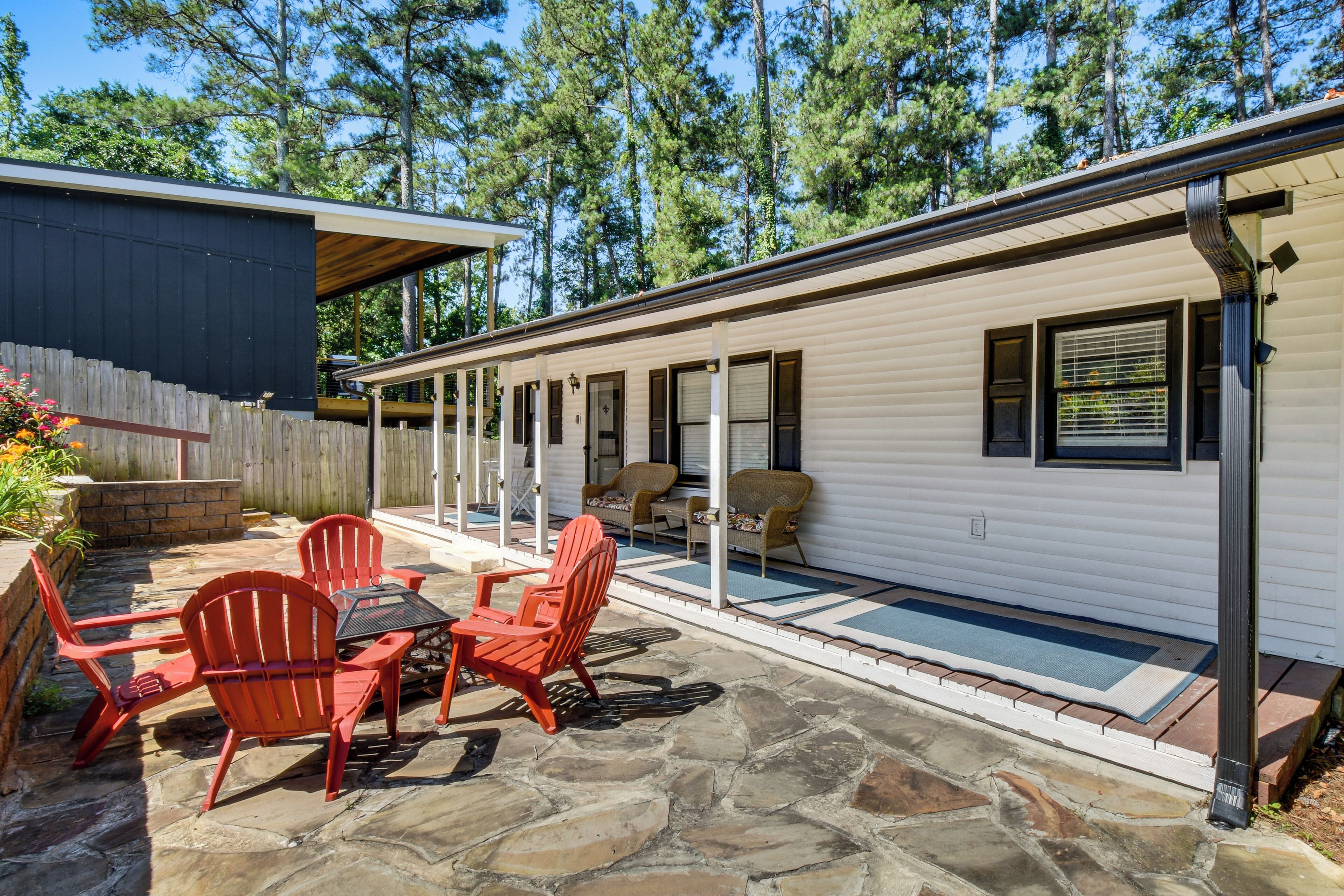A mobile home with a patio area featuring stone flooring and red Adirondack chairs.