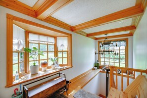 A room with wooden beams, a piano, a window with a view, and a staircase with a railing. - Waterfront Fox Lake Vacation Rental w/ Fire Pit! (Fox Lake)
