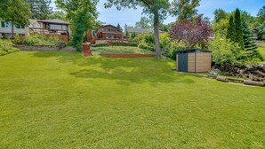 Ein gepflegter Rasen mit einer Holzterrasse und einem Gartenhaus.