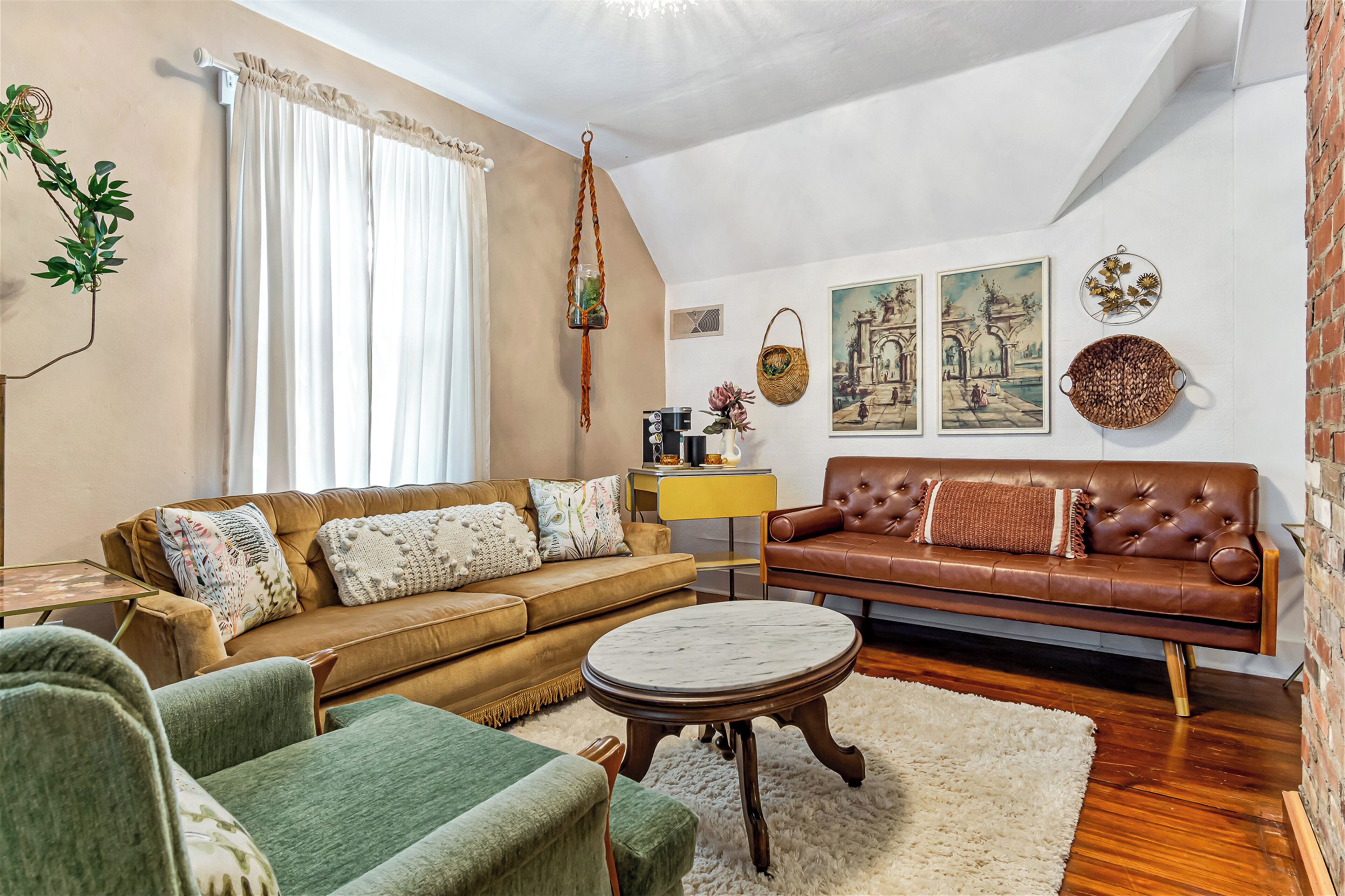 Una sala de estar con un sofá marrón, un sillón verde y una mesa de centro redonda.
