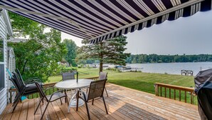 A wooden deck with a table and chairs, overlooking a lake and trees. - Lakefront Grant Cottage w/ Grill & Fire Pit! (Grant)