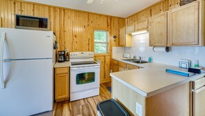 A kitchen with wooden walls, a white refrigerator, a stove, and a microwave. - Lakefront Grant Cottage w/ Grill & Fire Pit! (Grant)