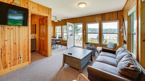 A wooden interior with a sofa, coffee table, and a TV mounted on the wall. - Lakefront Grant Cottage w/ Grill & Fire Pit! (Grant)