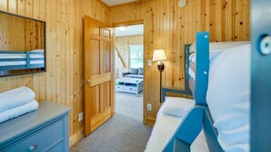 A wooden-paneled room with bunk beds, a desk with a mirror, and a lamp. - Lakefront Grant Cottage w/ Grill & Fire Pit! (Grant)