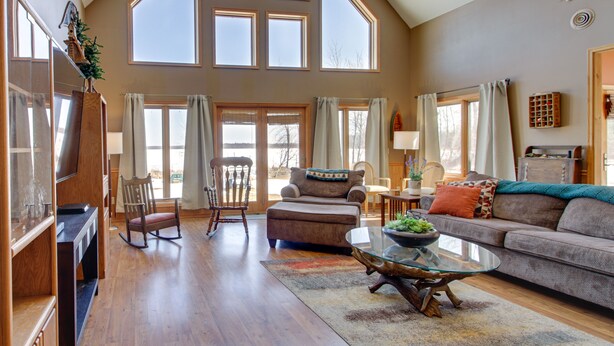A spacious living room with a high ceiling, large windows, a fireplace, and a cozy seating area. - Lakefront Grand Rapids Vacation Rental w/ Dock! (Grand Rapids)