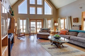 A spacious living room with a high ceiling, large windows, a fireplace, and a cozy seating area. - Lakefront Grand Rapids Vacation Rental w/ Dock! (Grand Rapids)