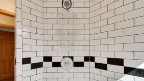 A corner of a bathroom with white and black checkered tiles, a white towel rack, and a white towel dispenser. - Lakefront Grand Rapids Vacation Rental w/ Dock! (Grand Rapids)