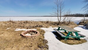 A picnic table and a fire pit in a snowy landscape with a clear sky. - Lakefront Grand Rapids Vacation Rental w/ Dock! (Grand Rapids)