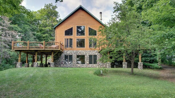 A log cabin with a stone foundation, a wooden deck, and a stone chimney. - Pokegama Lake Vacation Rental w/ Shared Boat Dock! (Grand Rapids)