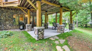 A covered outdoor patio with stone pillars, a stone fireplace, and outdoor seating. - Pokegama Lake Vacation Rental w/ Shared Boat Dock! (Grand Rapids)