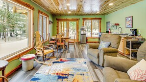 A cozy cabin interior with a dining area, a living room with a sofa and chairs, and a kitchen area. - Pokegama Lake Vacation Rental w/ Shared Boat Dock! (Grand Rapids)
