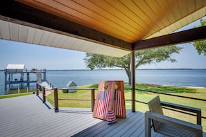 Une terrasse en bois offrant une vue sur l’eau, un espace abrité avec un banc, et une petite décoration à l’effigie du drapeau américain.