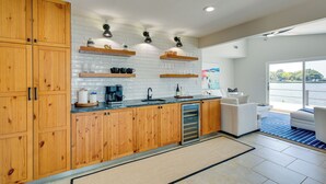 A modern kitchen with wooden cabinets, a built-in oven, and a large window overlooking a body of water. - Cedar Creek Lake Views: Gorgeous Mabank House! (Mabank)