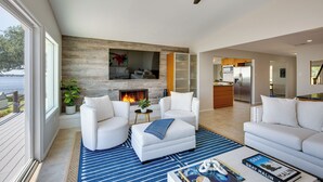 A modern living room with a fireplace, white sofas, and a view of the sea. - Cedar Creek Lake Views: Gorgeous Mabank House! (Mabank)