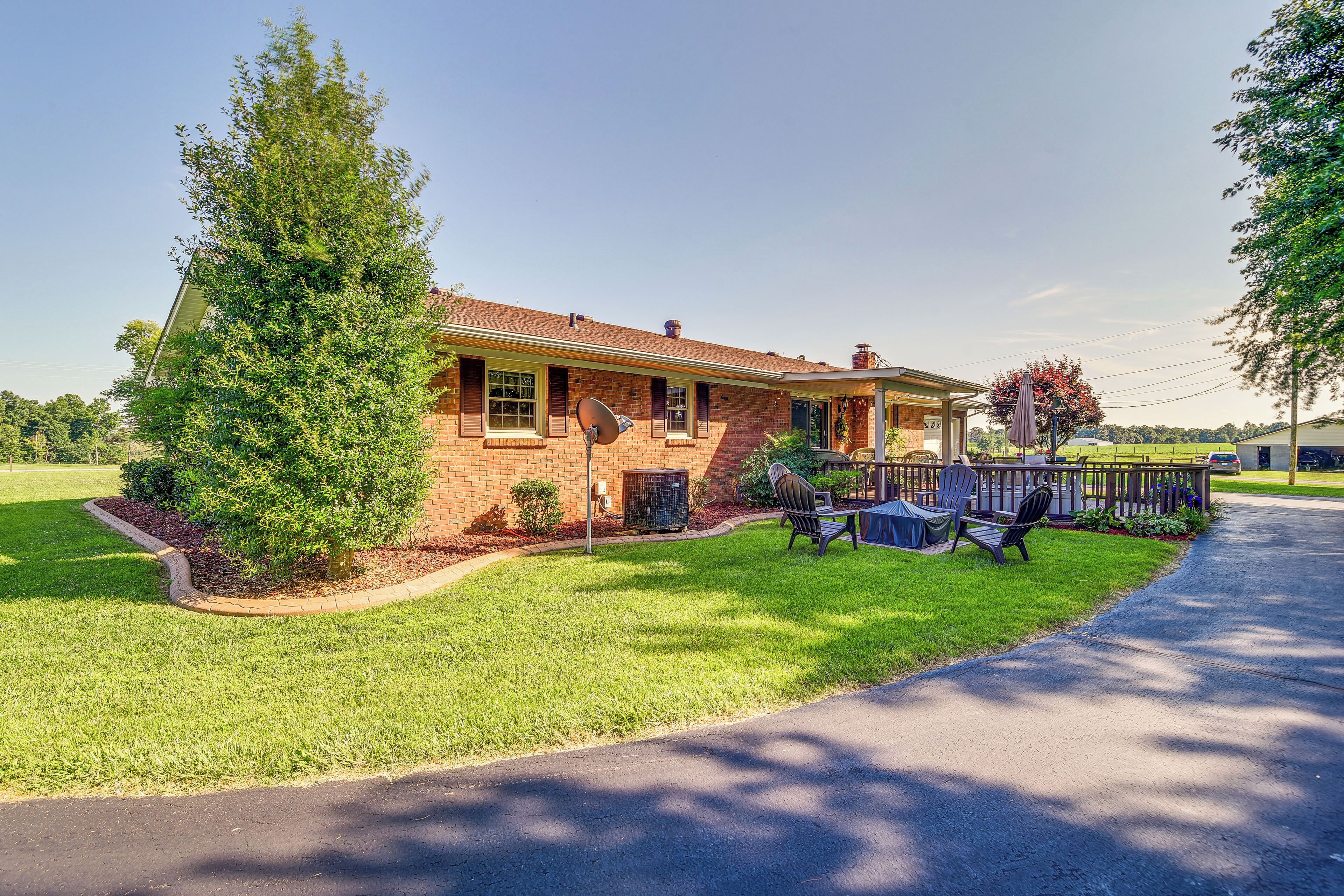 A brick house with a well-maintained lawn, a satellite dish, and outdoor furniture.