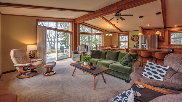 A spacious living room with a green sofa, a leather recliner, and a wooden coffee table. - Bear Lake Nature Escape! Fish, Hike, Relax (Rice Lake)