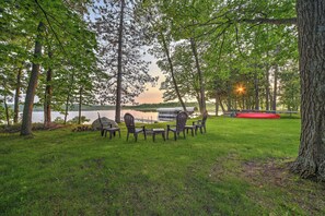 A grassy area with a table and chairs, surrounded by trees and a lake view. - Bear Lake Nature Escape! Fish, Hike, Relax (Rice Lake)