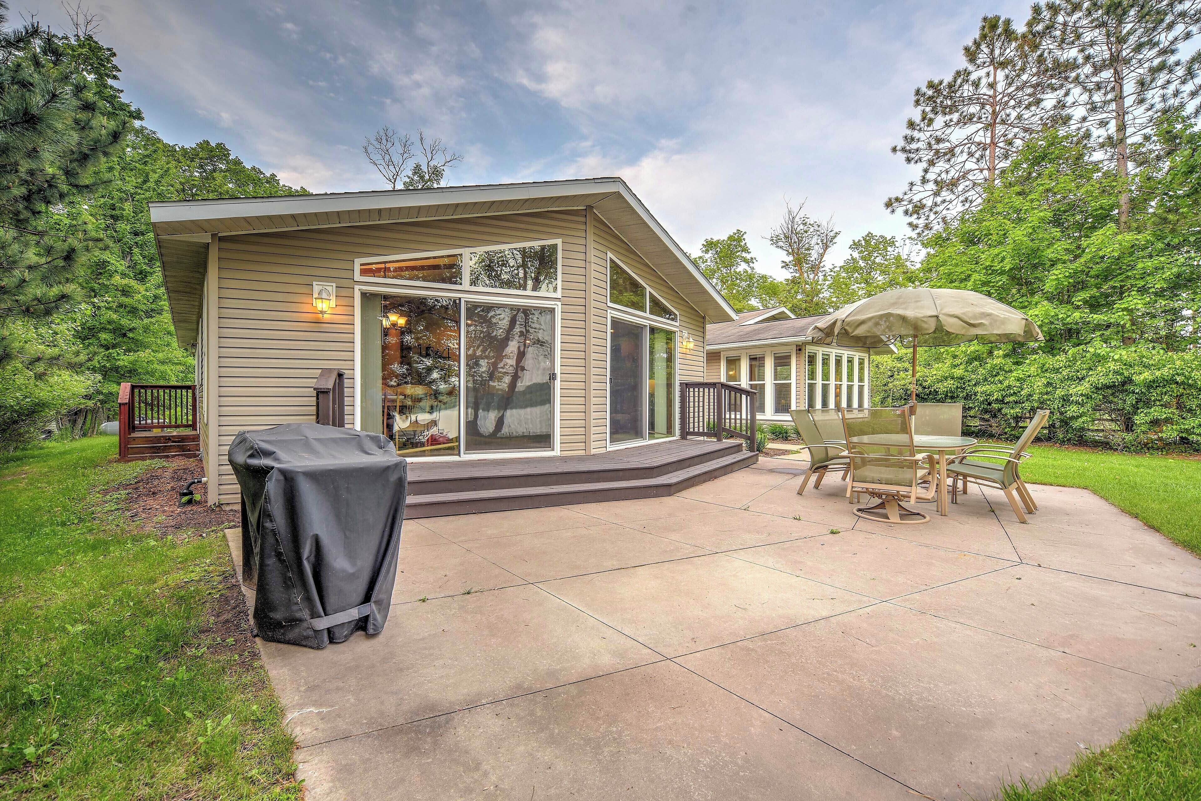 Une maison avec un patio, un barbecue couvert et une table avec des chaises.