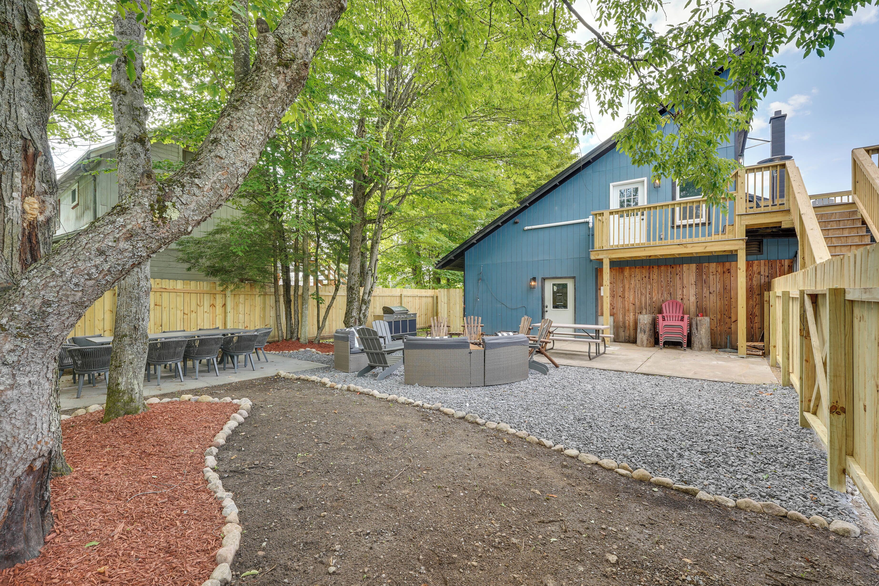 A backyard with a circular seating area, a wooden deck, and a blue building with a balcony.