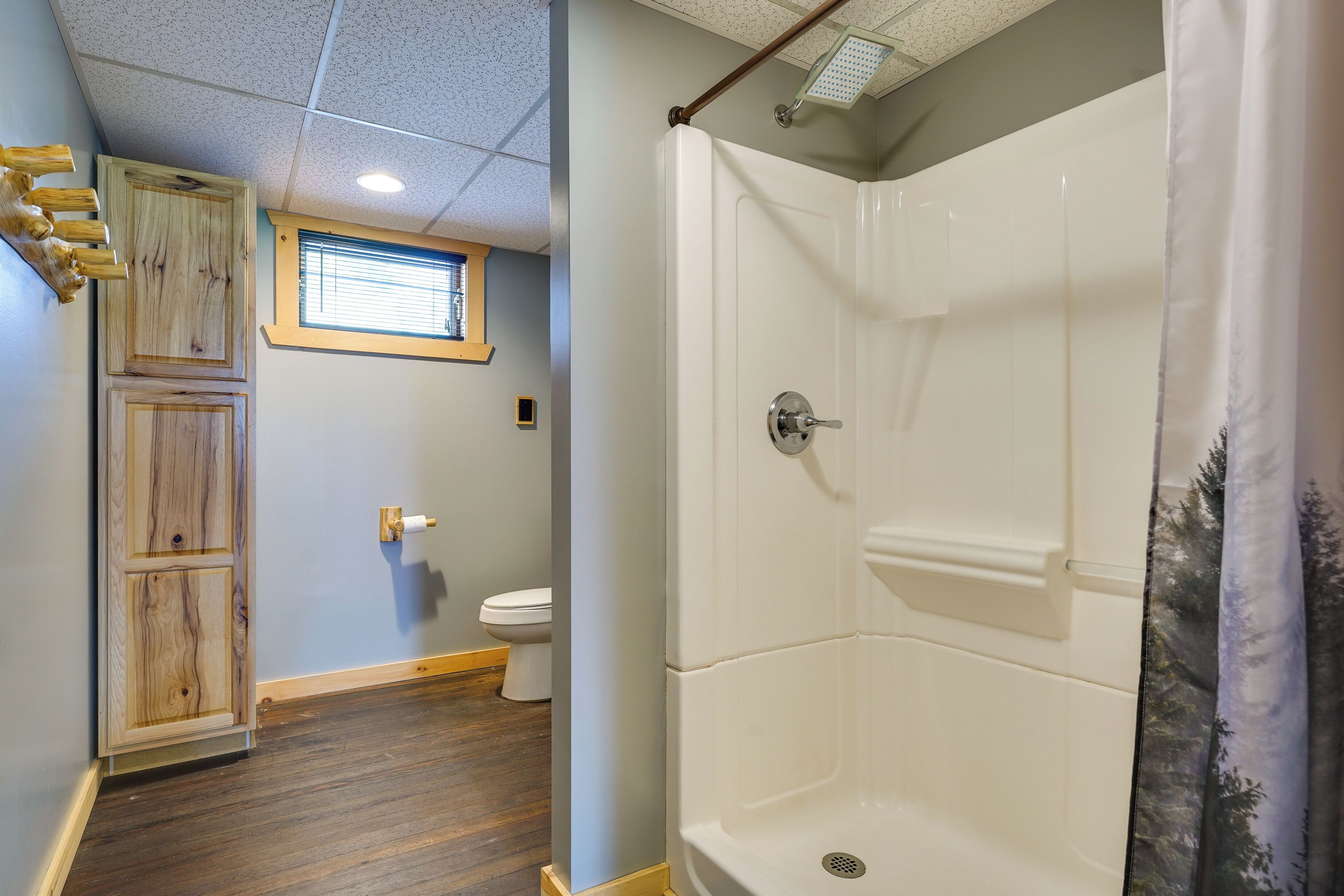 A bathroom with a shower, toilet, and wooden cabinetry.