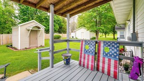 A wooden deck with a railing, a small shed, and a painted American flag. - Charming St James Home Near Maramec Spring Park! (St. James)