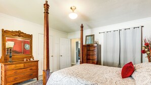 A bedroom with a four-poster bed, a wooden dresser, a mirror, and a door leading to another room. - Charming St James Home Near Maramec Spring Park! (St. James)