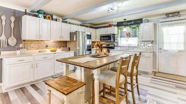 A kitchen with white cabinets, a wooden island, and a striped floor. - Charming St James Home Near Maramec Spring Park! (St. James)