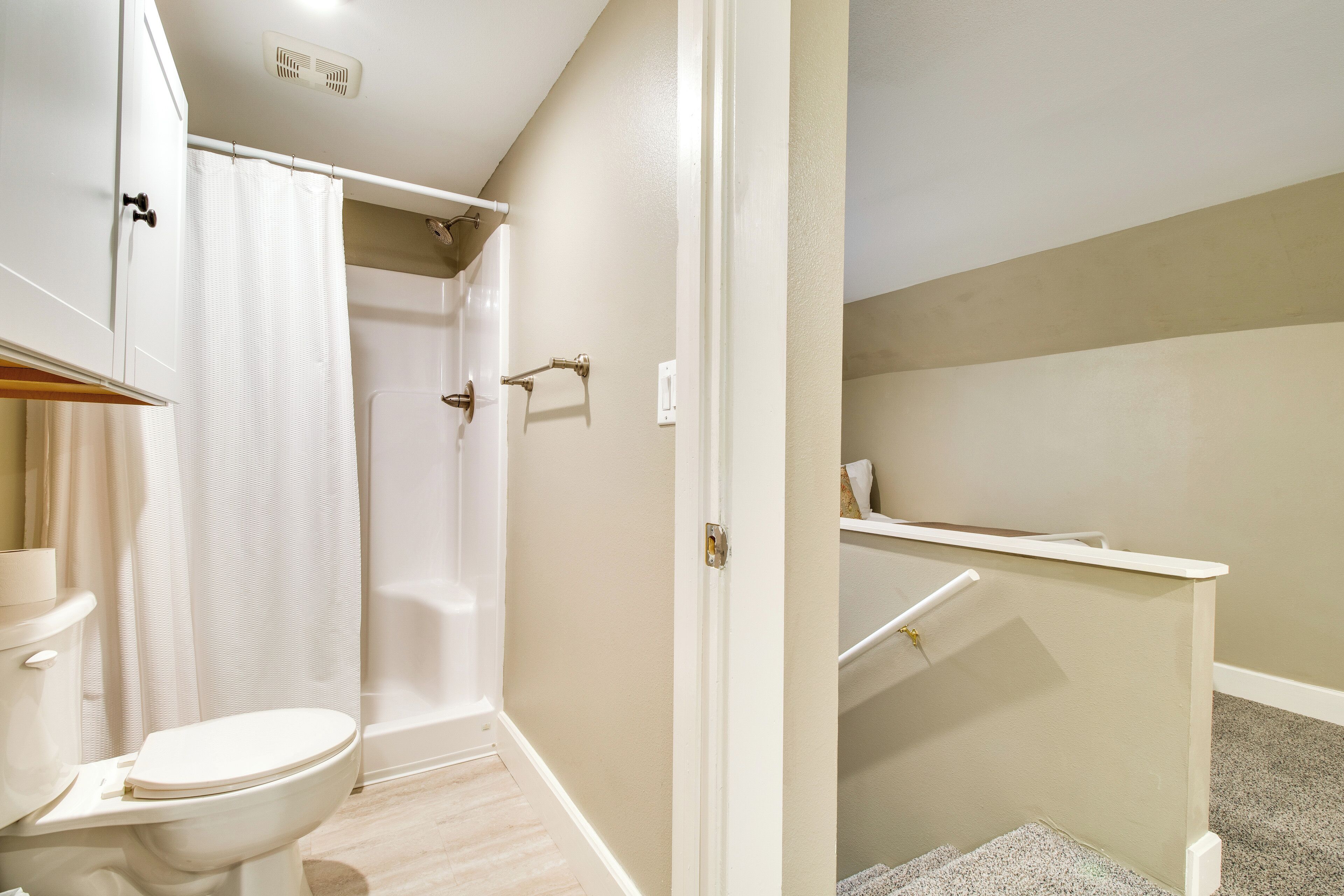 A bathroom with a toilet, shower, and sink.