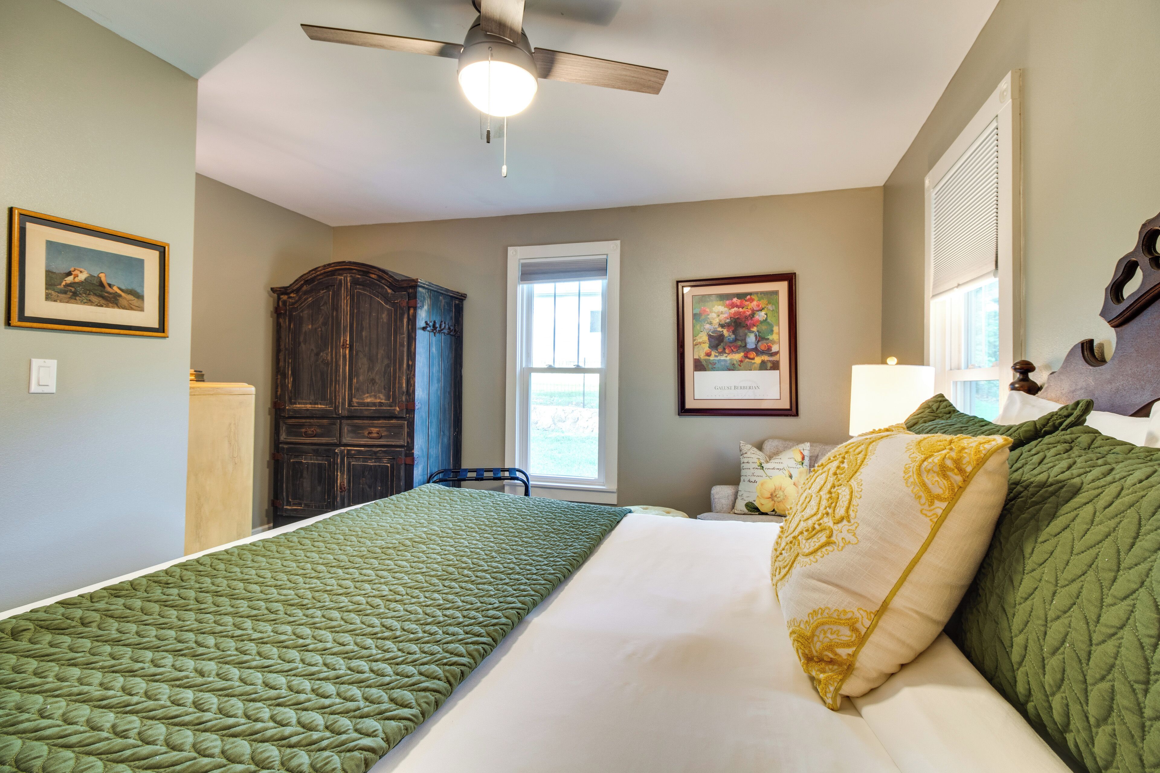 A bedroom with a bed, a ceiling fan, a window, and a wardrobe.