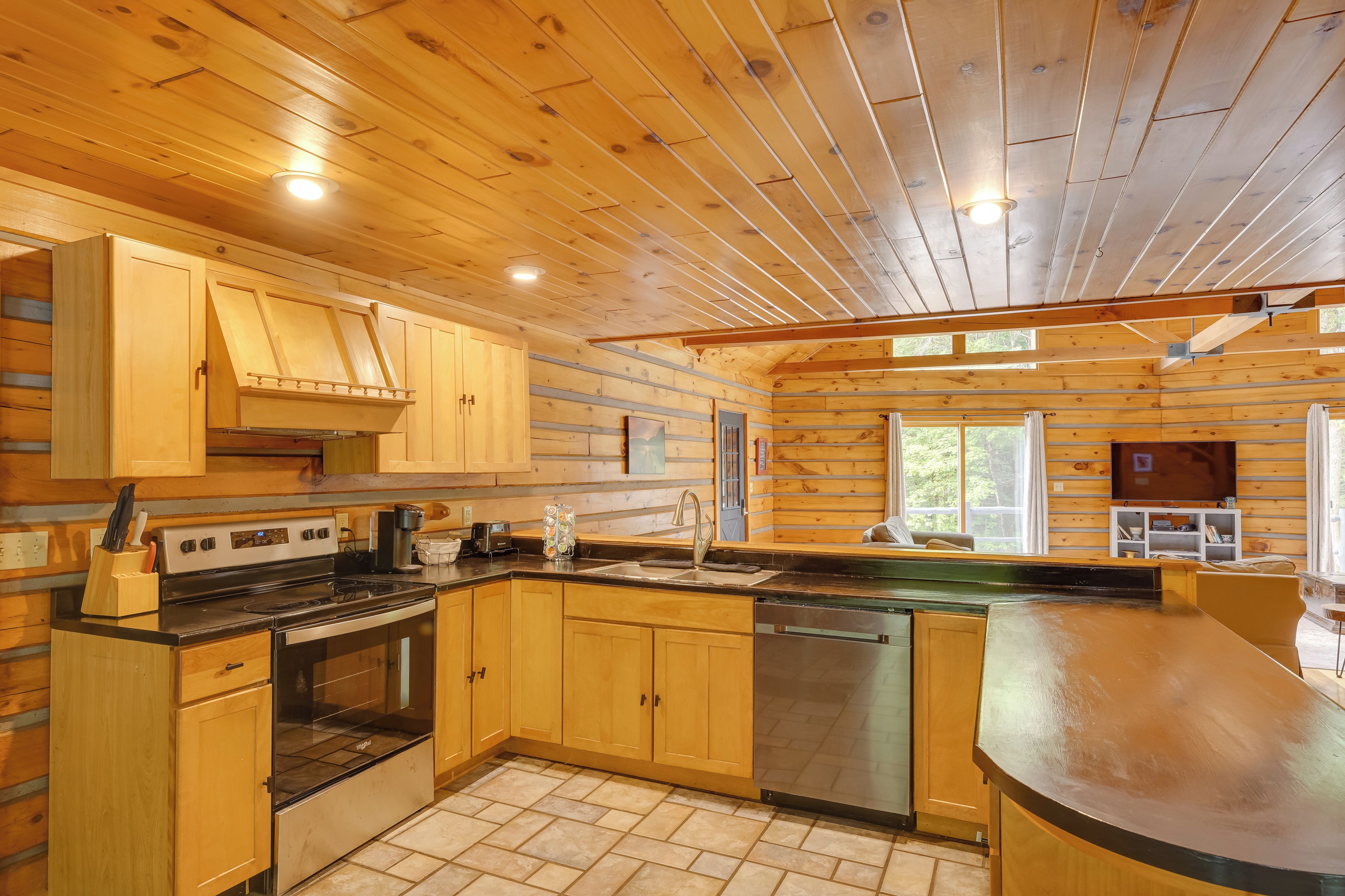 A kitchen with wooden cabinets, a stove, and a dishwasher.