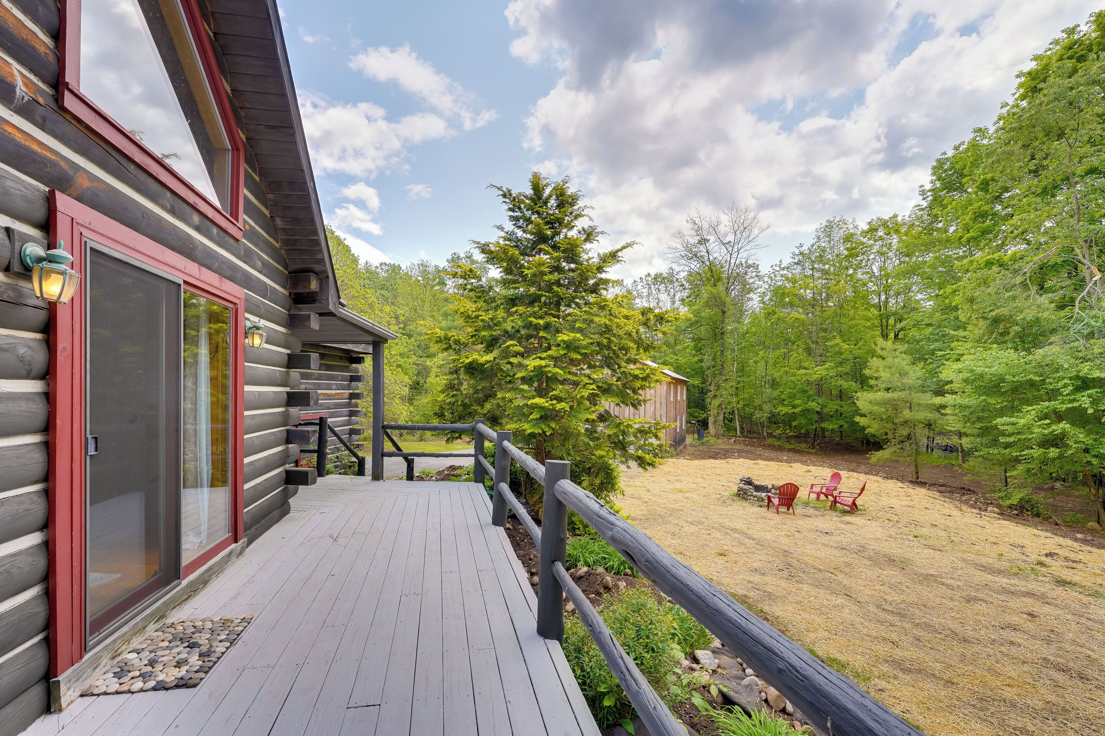 A wooden deck with a railing, a door, and a small outdoor seating area with chairs.